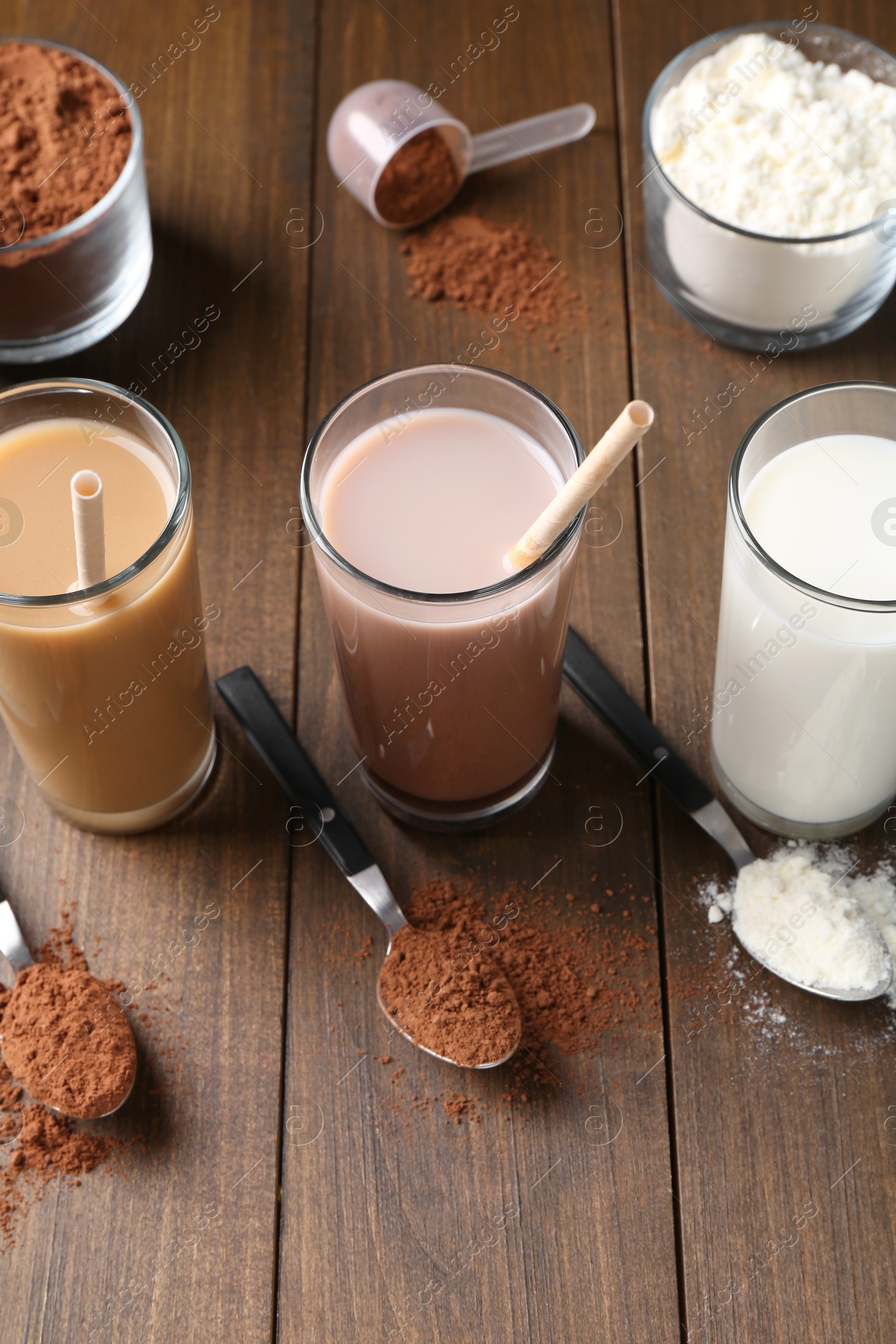 Photo of Delicious protein shakes in glasses, powder and spoons on wooden table