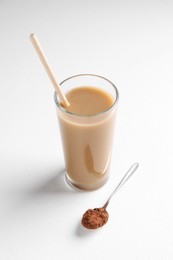 Photo of Delicious protein shake in glass and spoon with powder on white background