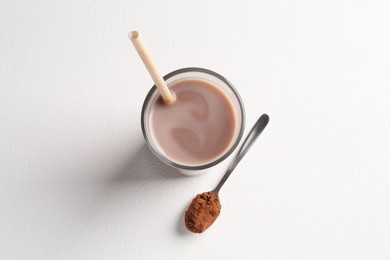 Photo of Delicious protein shake in glass and spoon with powder on white background, top view