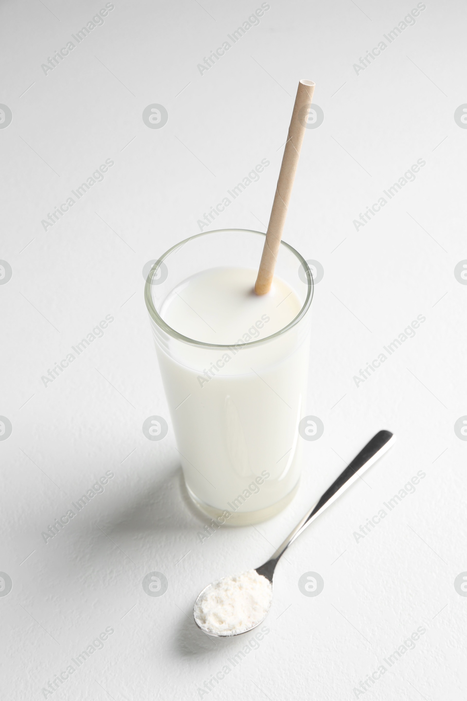 Photo of Delicious protein shake in glass and spoon with powder on white background