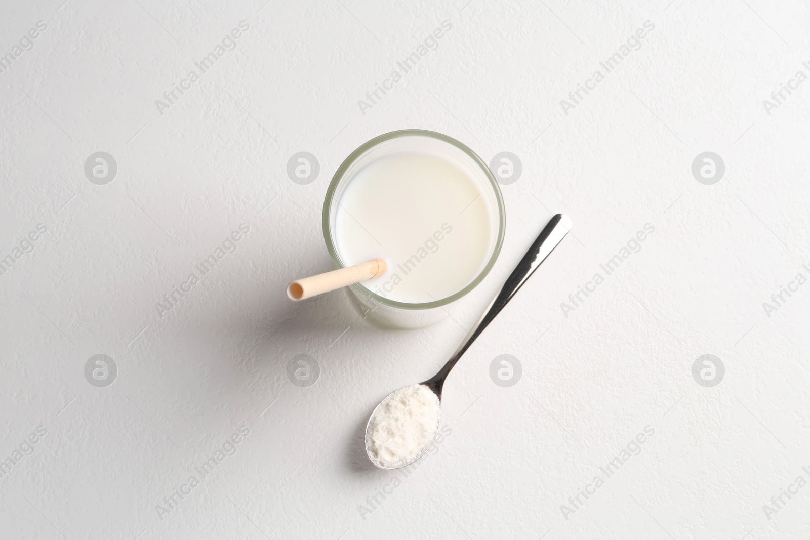 Photo of Delicious protein shake in glass and spoon with powder on white background, top view