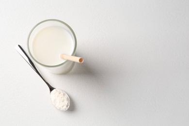 Photo of Delicious protein shake in glass and spoon with powder on white background, top view. Space for text