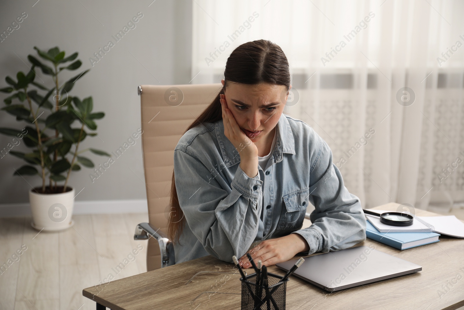 Photo of Embarrassed woman at wooden table with laptop in office