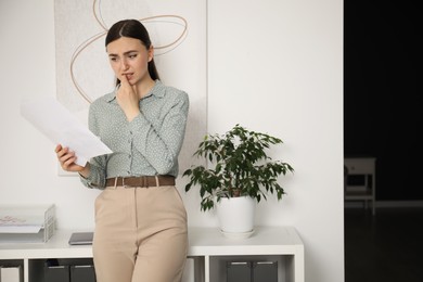 Photo of Embarrassed young woman with documents in office