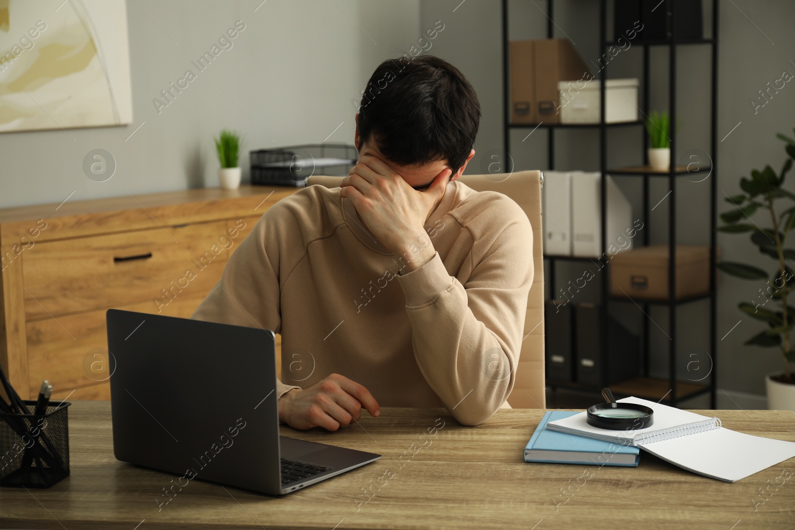 Photo of Embarrassed man at wooden table with laptop in office