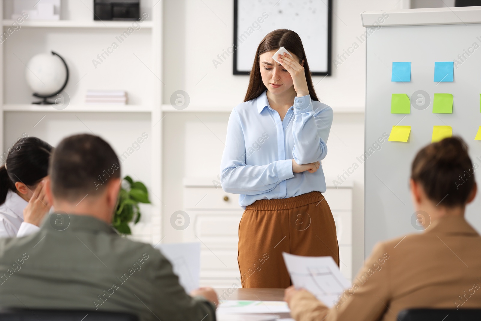 Photo of Woman with tissue feeling embarrassed during business meeting in office