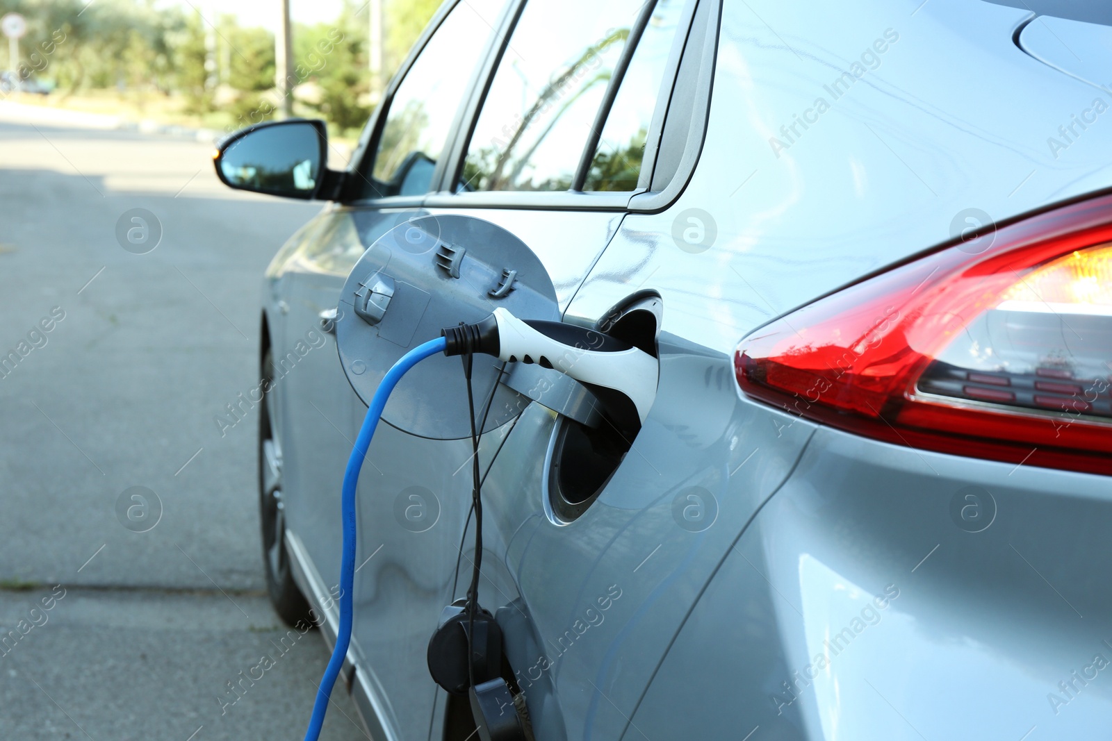 Photo of Charging modern electric car from station outdoors