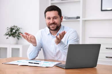 Photo of Consultant at table with laptop and documents in office