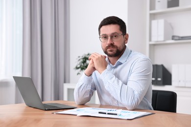 Consultant at table with laptop and documents in office