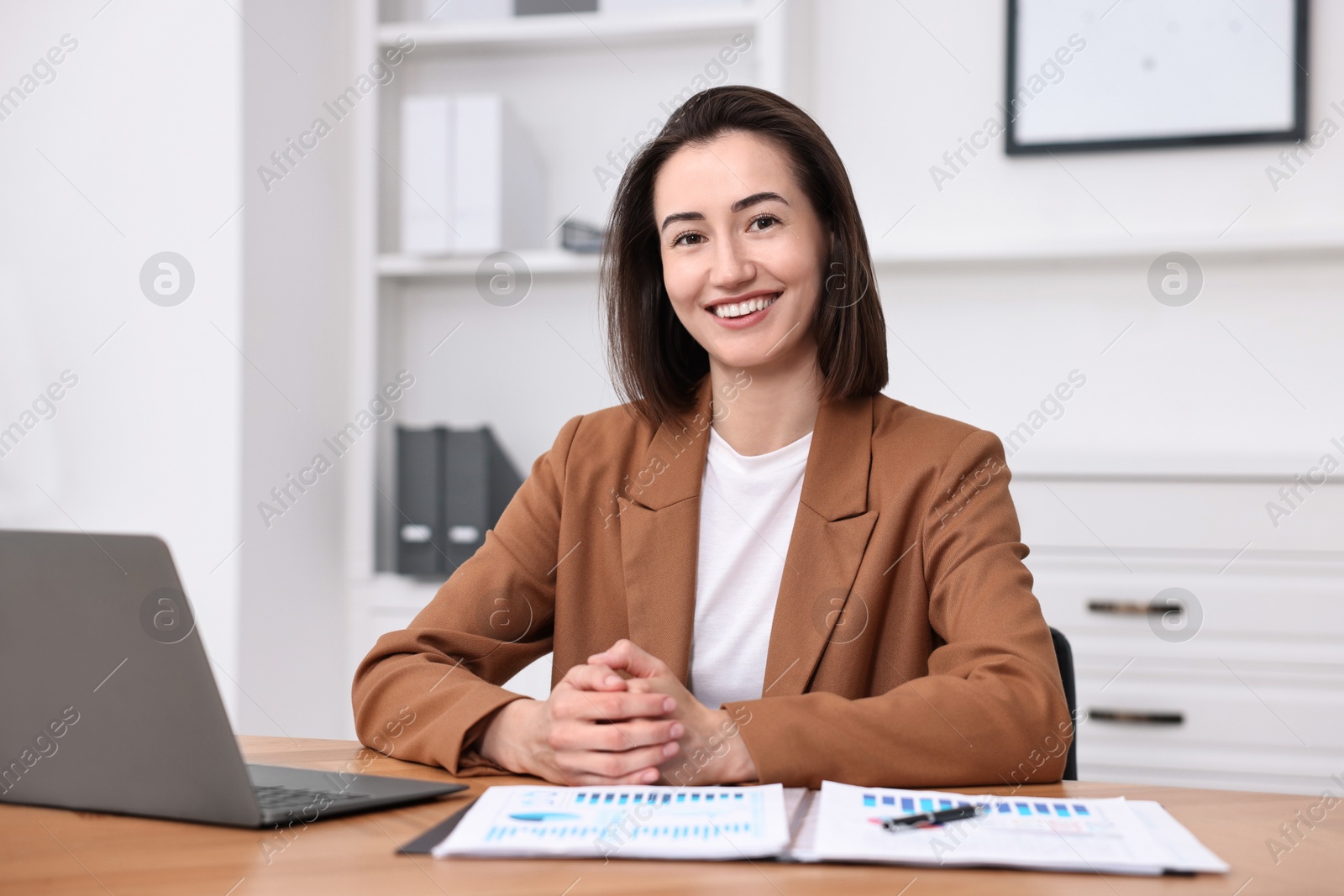 Photo of Consultant at table with laptop and documents in office