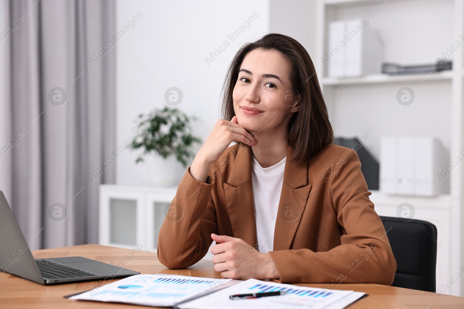 Photo of Consultant at table with documents and laptop in office