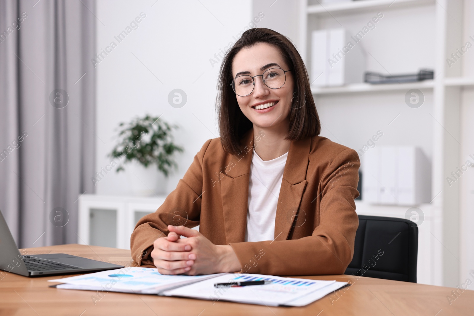 Photo of Consultant at table with documents and laptop in office