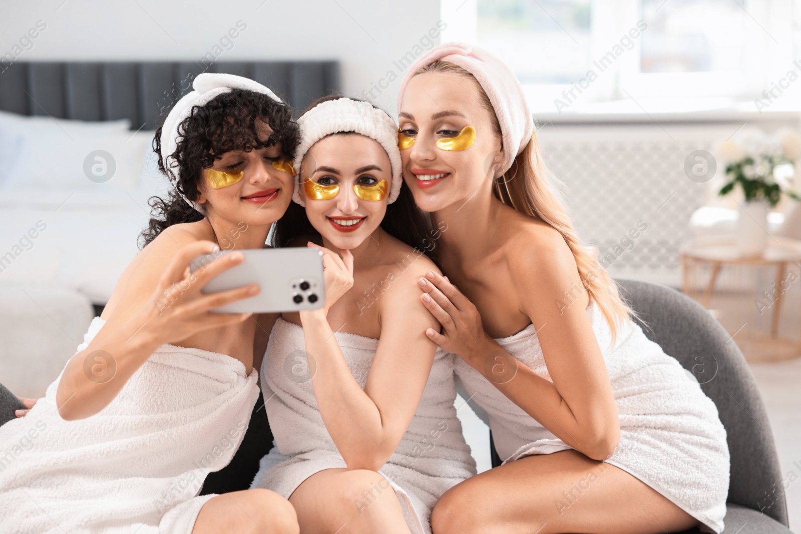 Photo of Happy friends with eye patches taking selfie indoors. Spa party