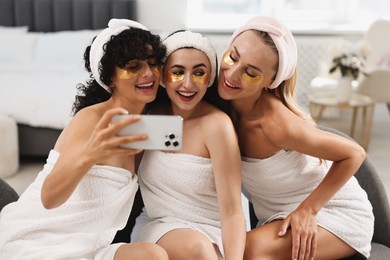 Photo of Happy friends with eye patches taking selfie indoors. Spa party