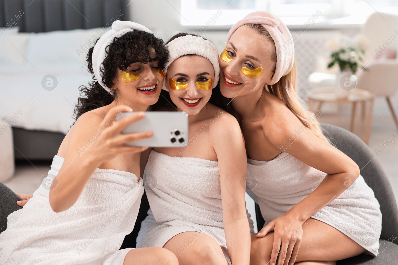 Photo of Happy friends with eye patches taking selfie indoors. Spa party