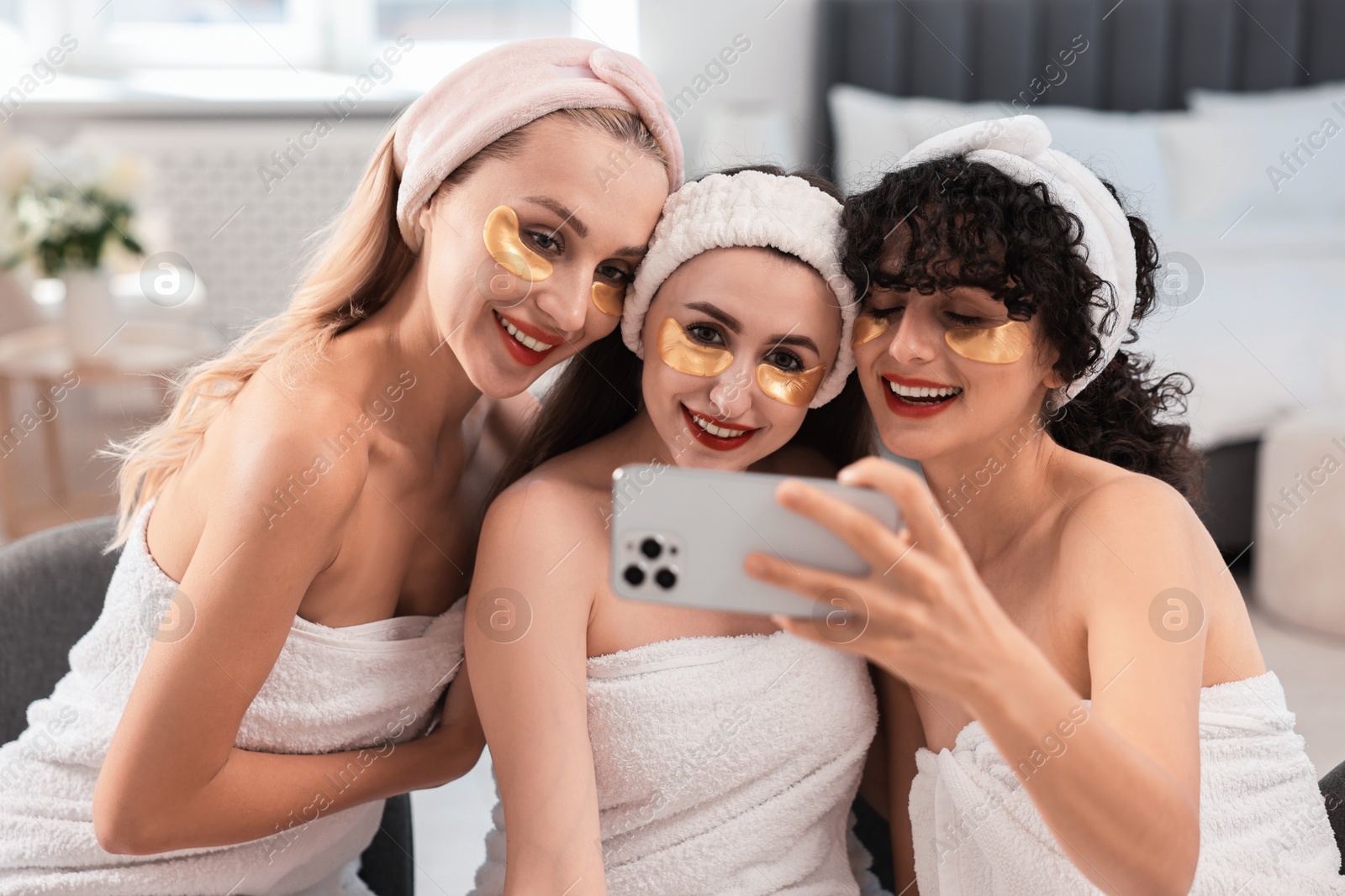 Photo of Happy friends with eye patches taking selfie indoors. Spa party