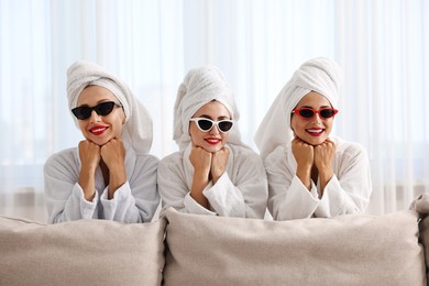 Happy friends in bathrobes with sunglasses indoors. Spa party