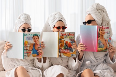 Photo of Friends in bathrobes with magazines on couch indoors. Spa party