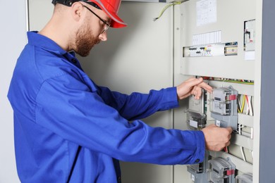 Electrician installing electricity meter indoors, closeup view