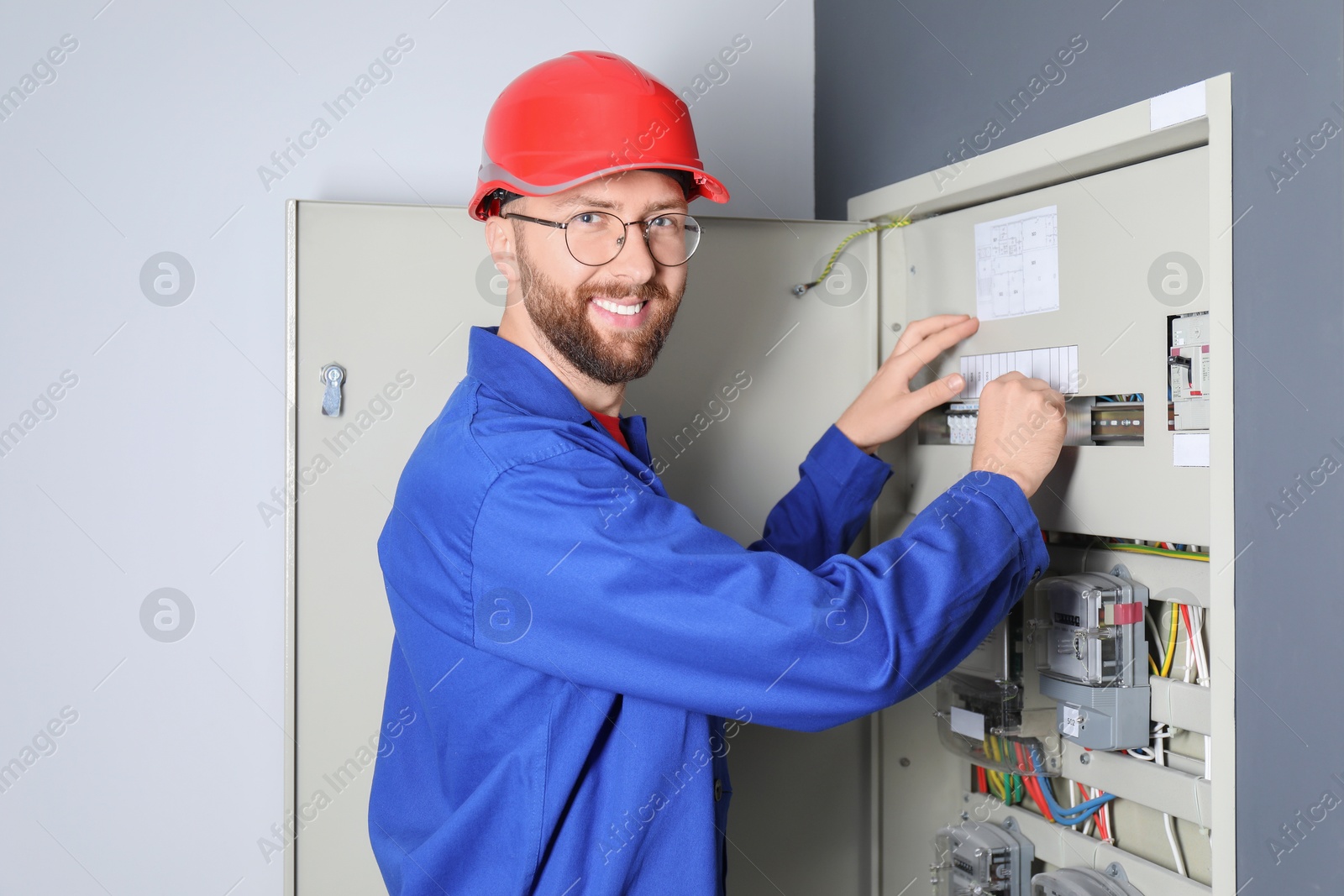 Photo of Electrician wearing uniform installing electricity meter indoors