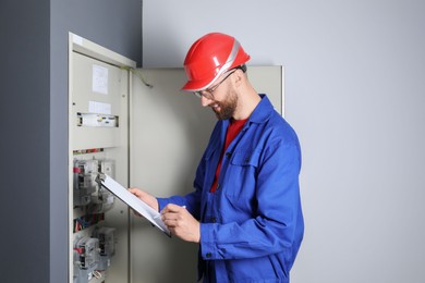 Photo of Technician worker with clipboard inspecting electricity meter