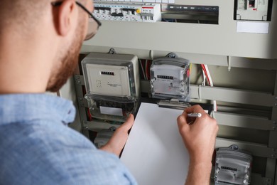 Photo of Technician worker with clipboard inspecting electricity meter, closeup