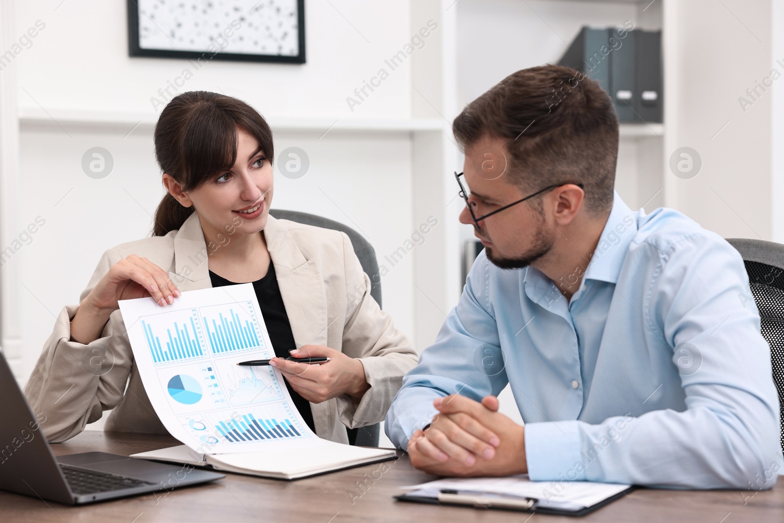 Photo of Smiling consultant working with client at table in office. Business meeting