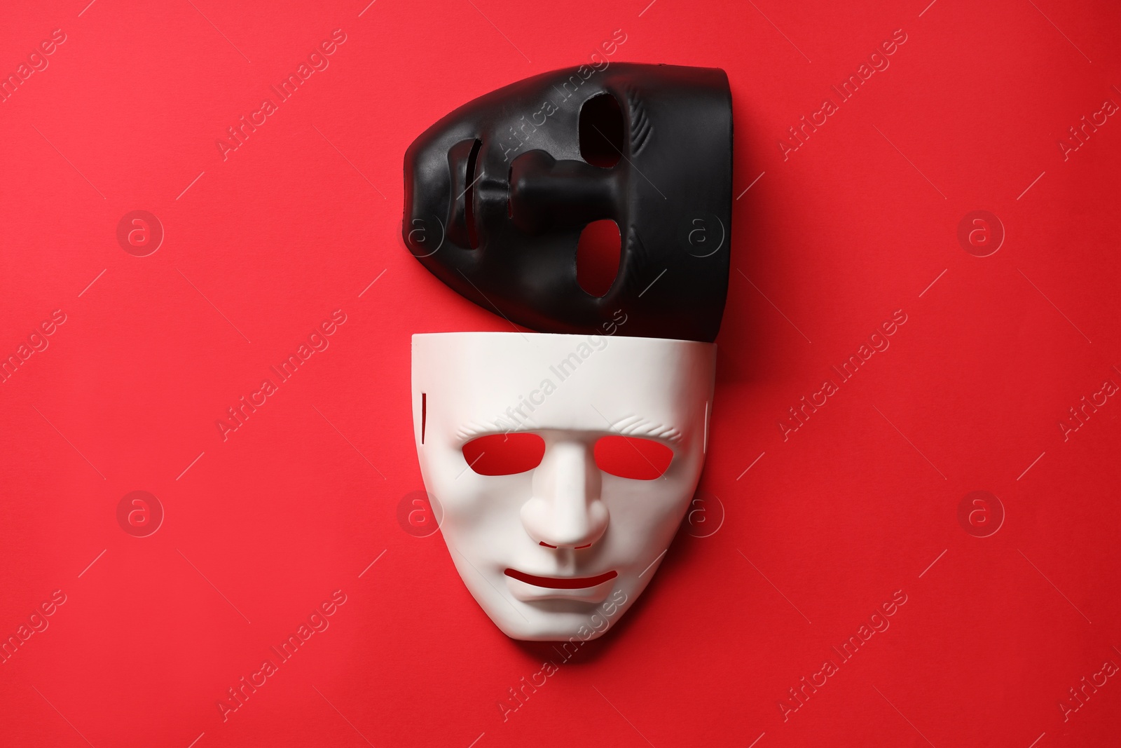 Photo of Theater arts. White and black masks on red background, top view