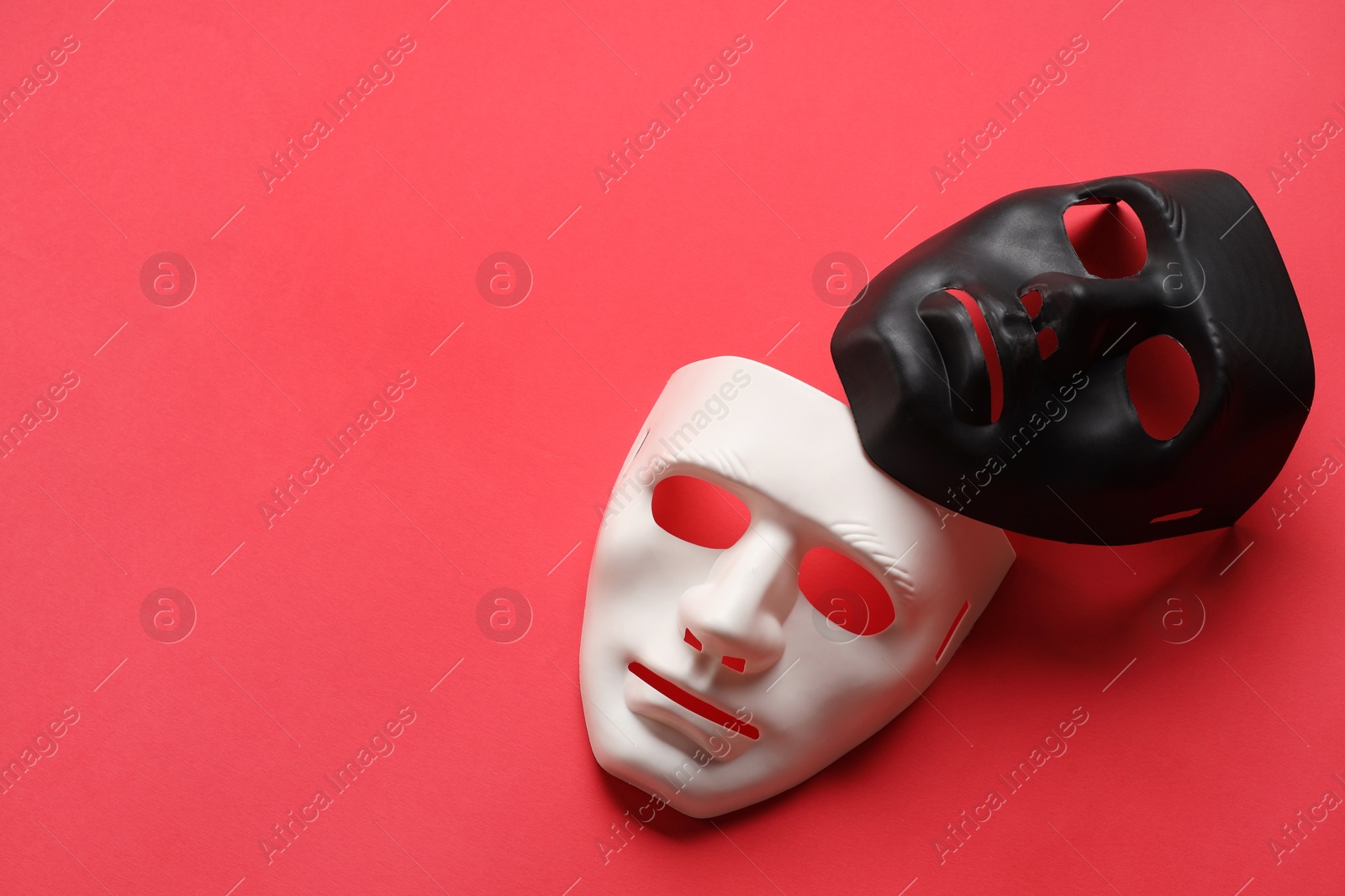 Photo of Theater arts. White and black masks on red background, above view. Space for text