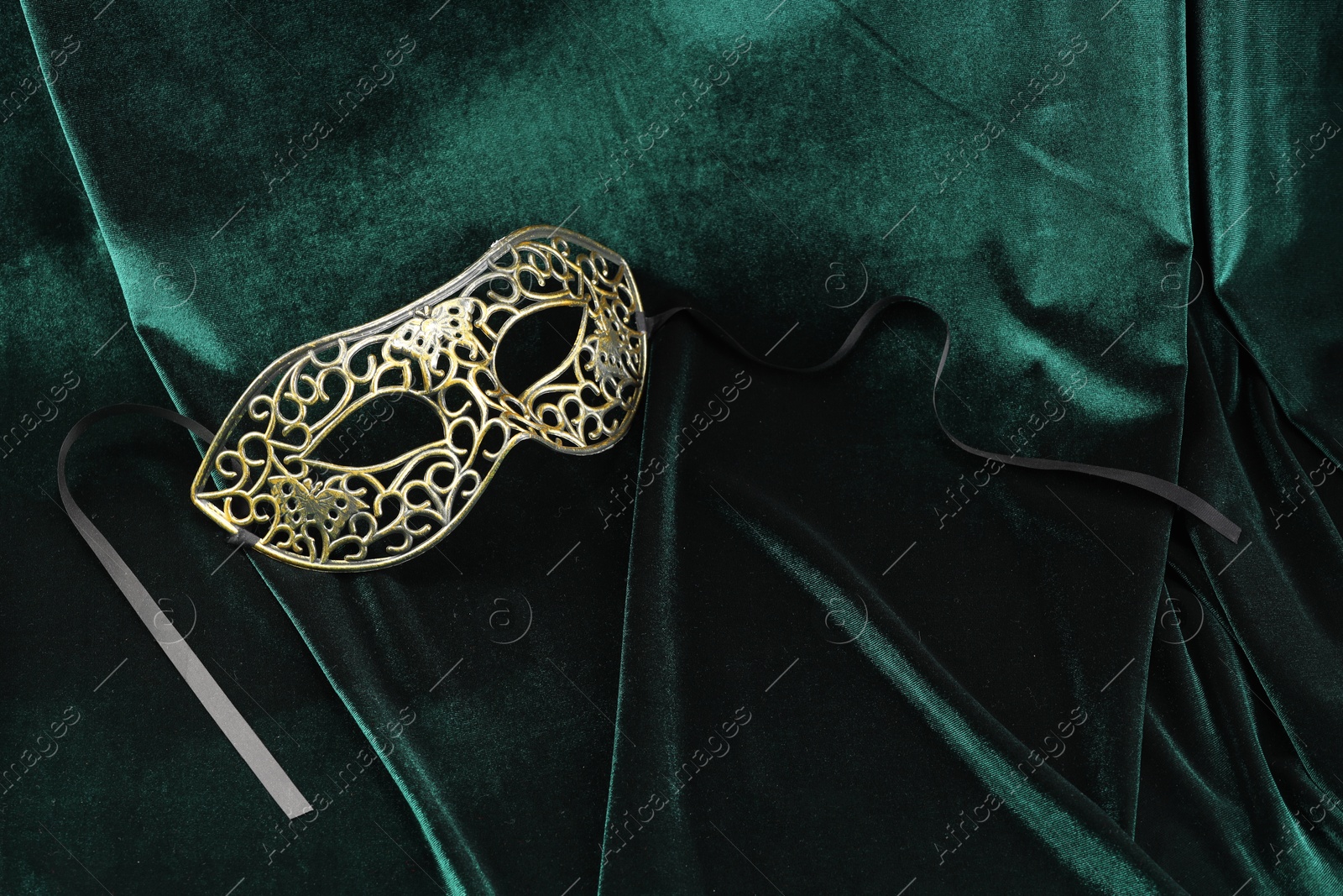 Photo of Theater arts. Venetian carnival mask on green fabric, top view. Space for text