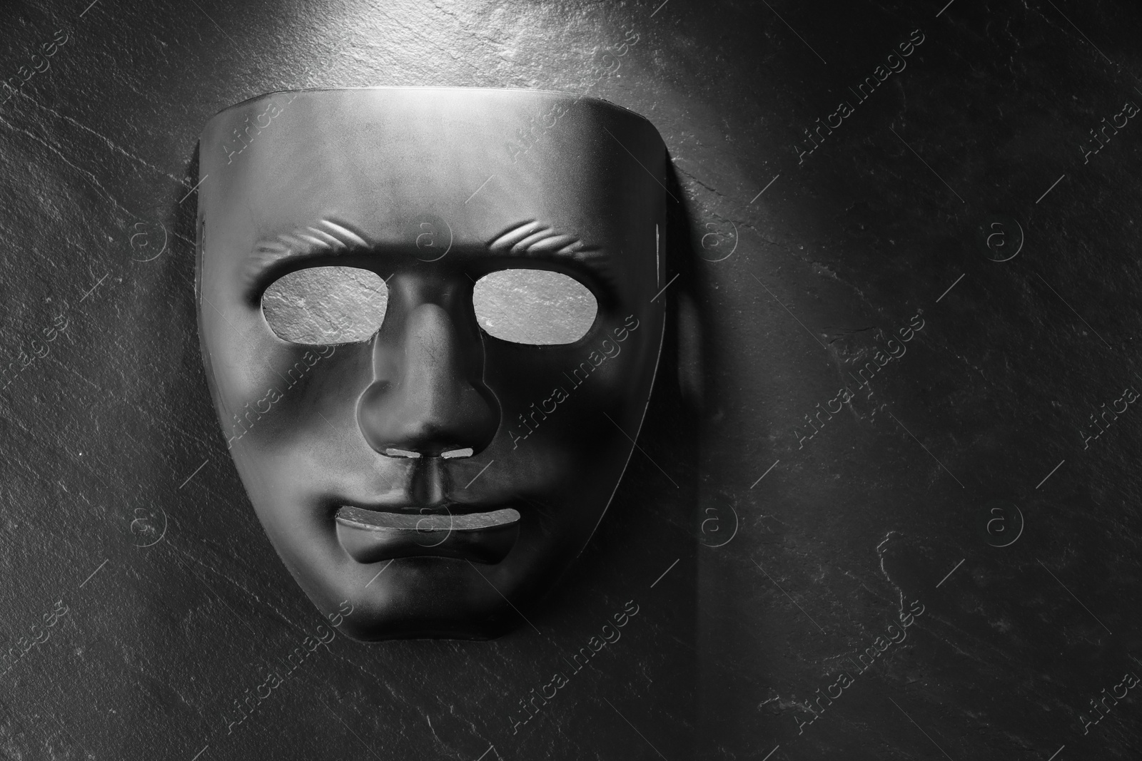 Photo of Plastic face mask on black slate surface, top view and space for text. Theatrical performance