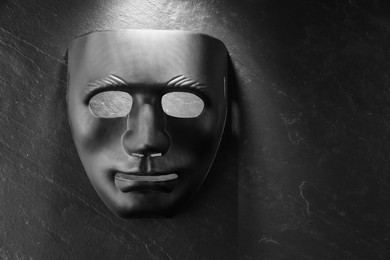 Photo of Plastic face mask on black slate surface, top view and space for text. Theatrical performance