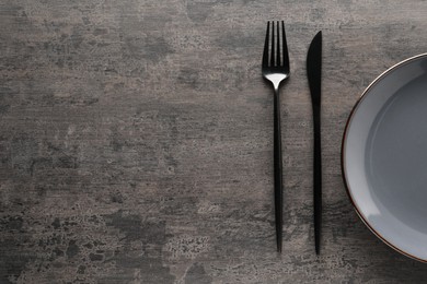 Stylish cutlery and plate on grey table, top view. Space for text