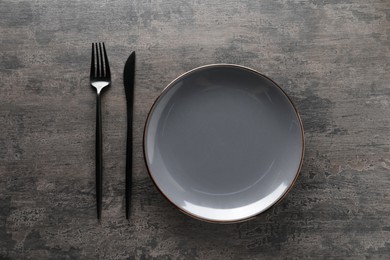 Photo of Stylish cutlery and plate on grey table, top view