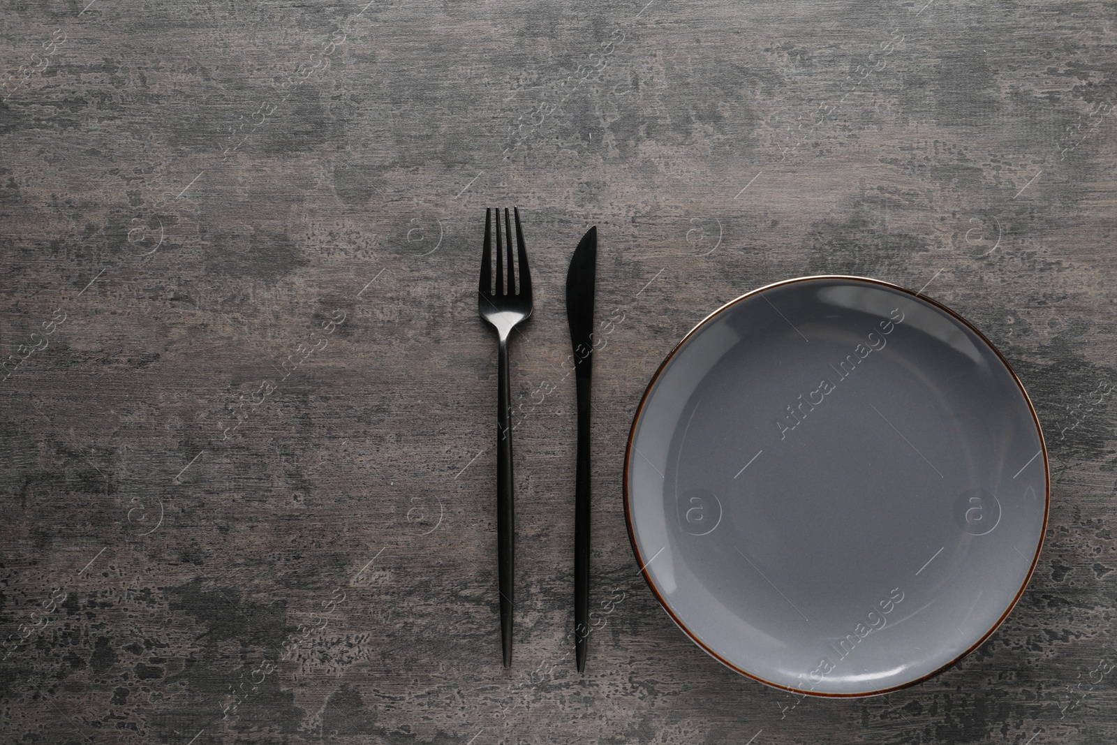 Photo of Stylish cutlery and plate on grey table, top view. Space for text