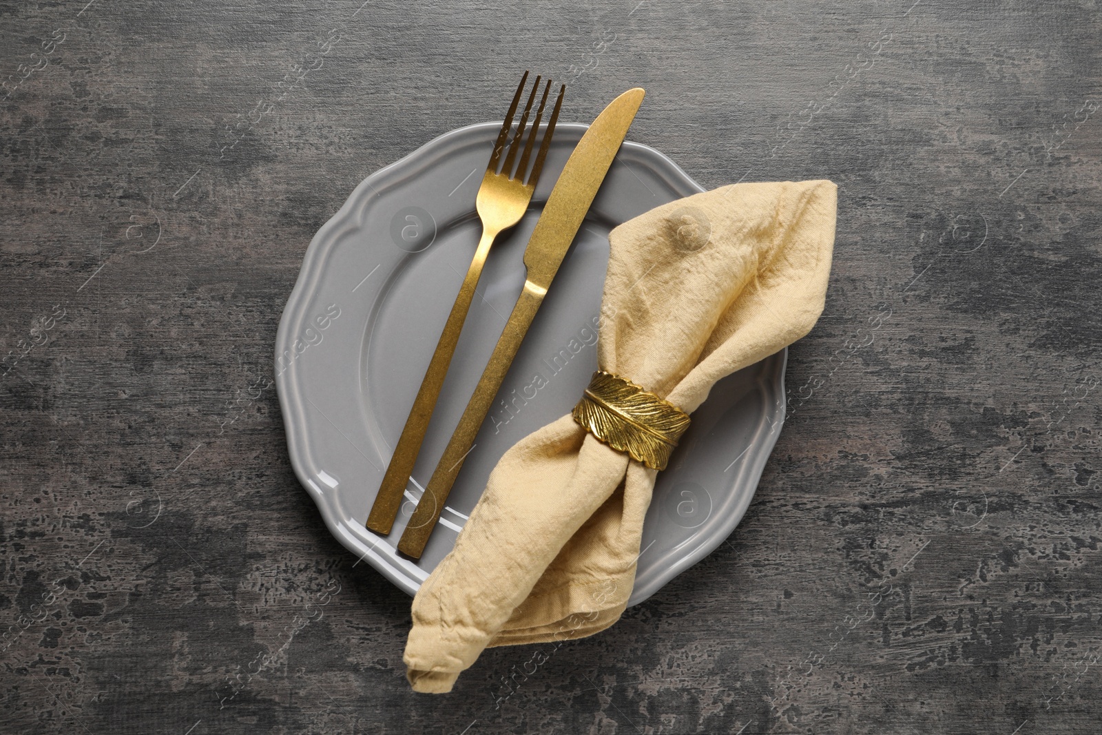 Photo of Stylish cutlery, plate and napkin on grey table, top view