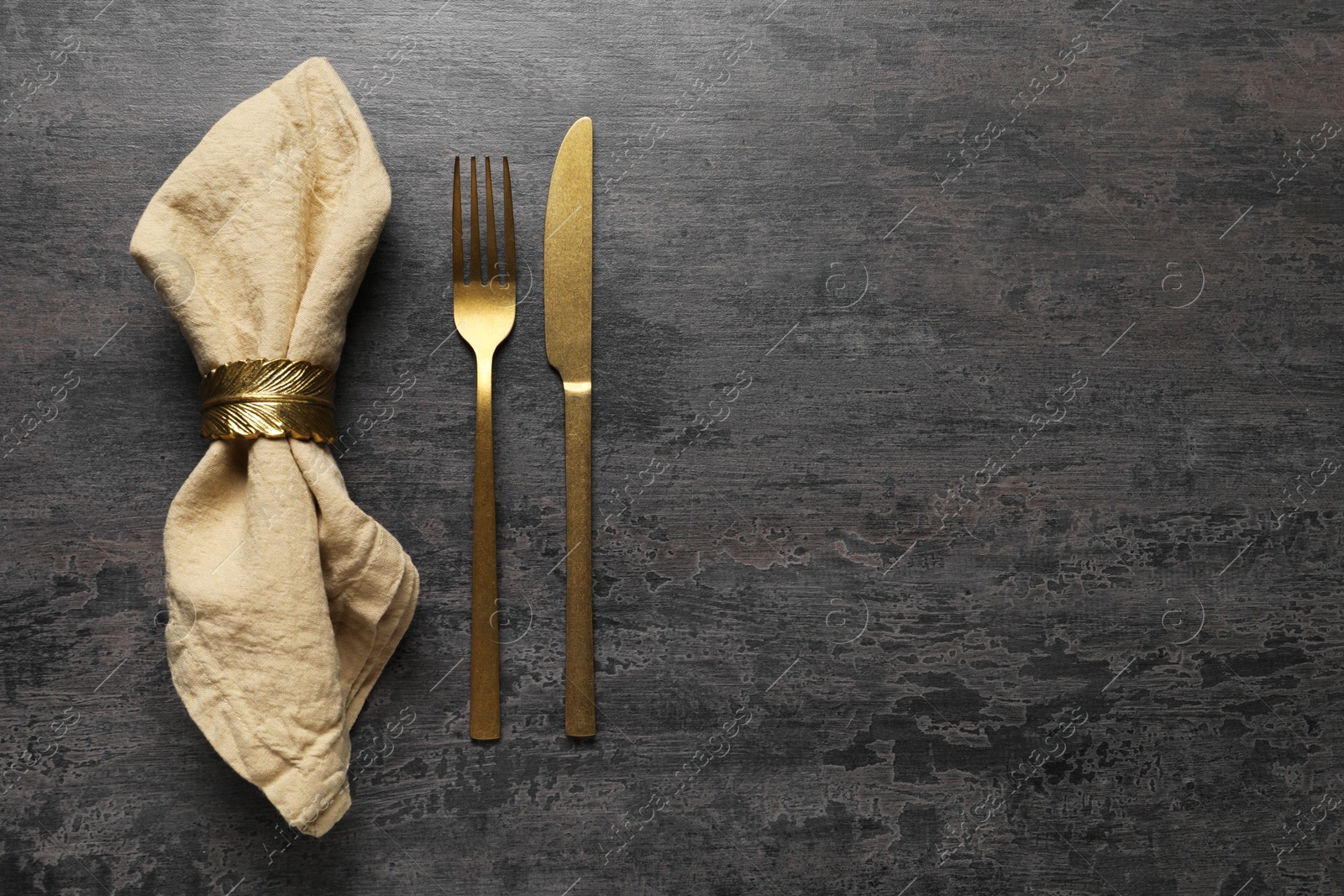 Photo of Stylish cutlery and napkin on grey table, top view. Space for text