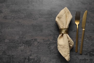 Photo of Stylish cutlery and napkin on grey table, top view. Space for text