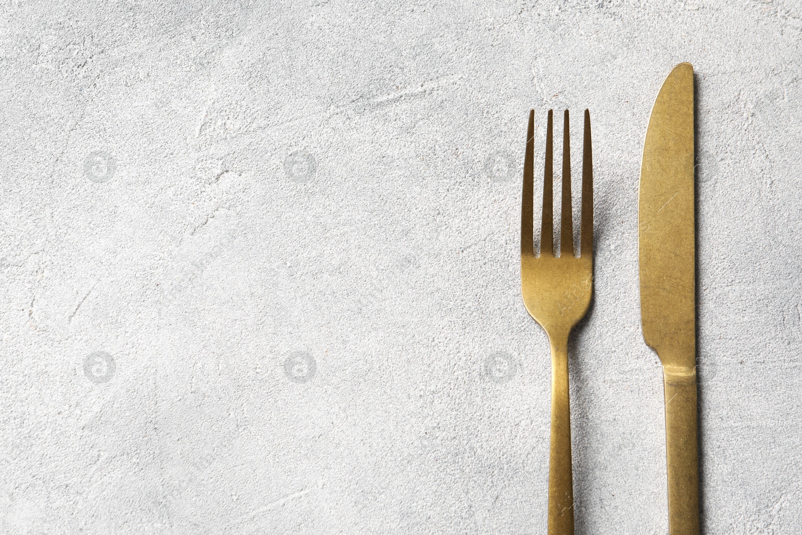 Photo of Stylish cutlery on light grey table, top view. Space for text