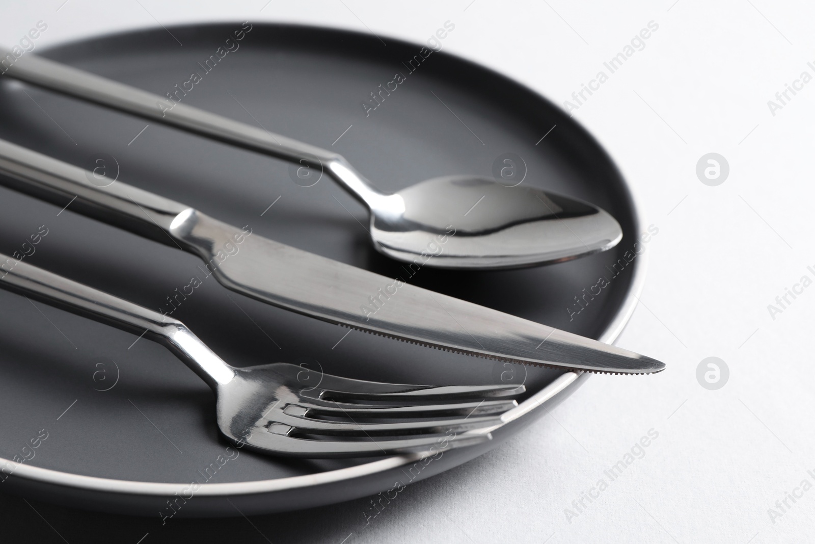 Photo of Stylish silver cutlery and plate on white background, closeup