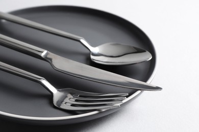 Stylish silver cutlery and plate on white background, closeup