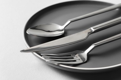 Stylish silver cutlery and plate on white background, closeup