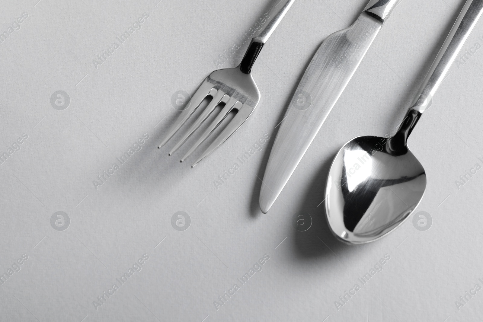 Photo of Stylish silver cutlery on white background, flat lay. Space for text