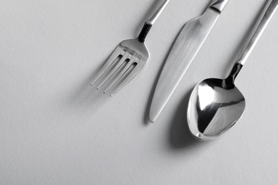 Stylish silver cutlery on white background, flat lay. Space for text