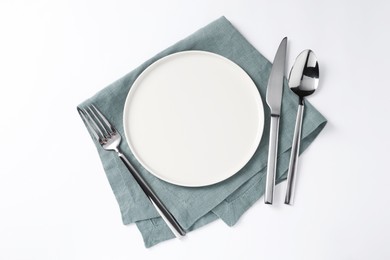 Photo of Stylish silver cutlery, plate and napkin on white background, top view