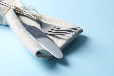 Stylish silver cutlery and napkin on light blue background, closeup