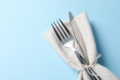 Photo of Stylish silver cutlery and napkin on light blue background, top view. Space for text