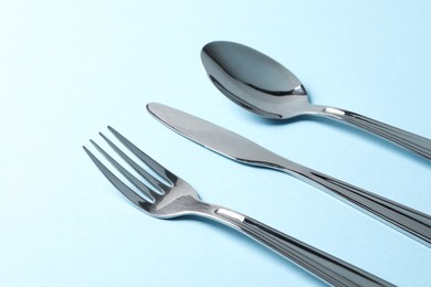 Stylish silver cutlery on light blue background