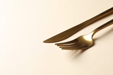 Photo of Stylish golden cutlery on beige background, space for text