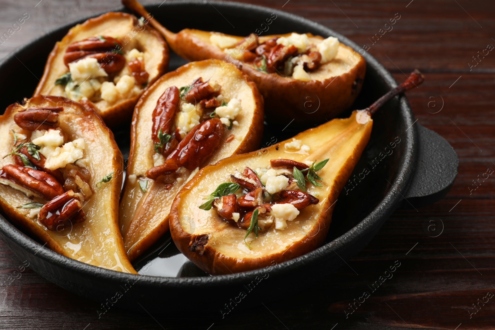 Photo of Delicious baked pears with nuts, blue cheese and honey on wooden table, closeup